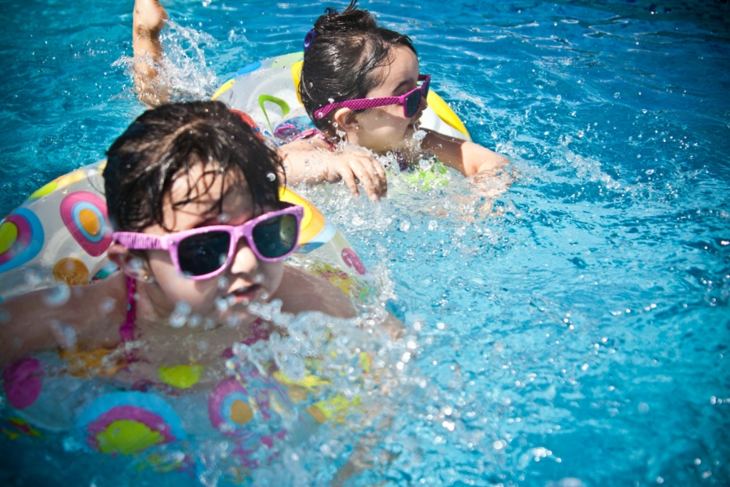 Children swimming in pool with floaties.