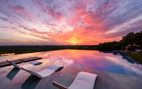 Sunset over a pool with pool chairs